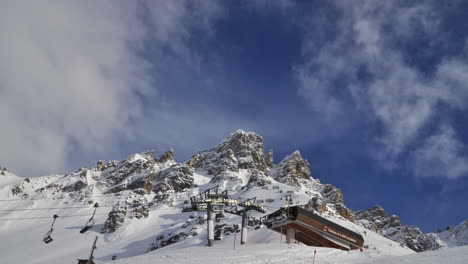 Time-lapse-of-a-ski-chair-lift-in-Meribel-in-the-French-Alps,-with-a-mountain-peak-and-moving-cloud