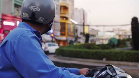 Man-on-motorbike-watching-the-traffic-while-passing-them-in-Asia,-Vietnam