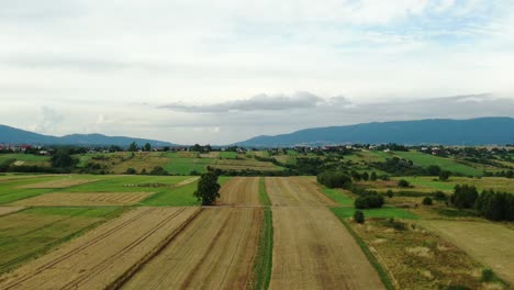 Aerial-view-of-the-countryside-with-fields-and-cyclist-with-mountains-in-the-background