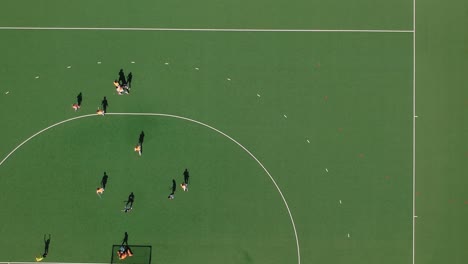 Eine-Tracking-Drohnenaufnahme-Eines-Feldhockey-Kurzecktors-Bei-Sonnigen-Bedingungen