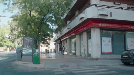 People-walk-past-Santander-bank-on-street-corner-in-Seville,-Spain