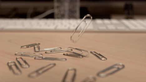 A-hand-full-of-paper-clips-slowly-dropping-onto-an-office-desk-in-slow-motion-a-little-bit-at-a-time