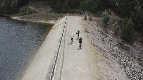 Three-mountain-biker-starting-on-the-dam-wall-of-lac-d'altenweiher-in-the-french-vosges