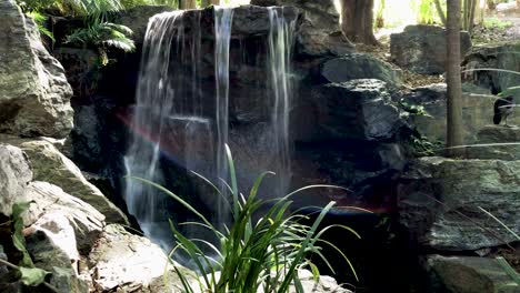 Ruhiger-Wasserfall-Mit-Regenbogen-Fließt-In-Den-Teich