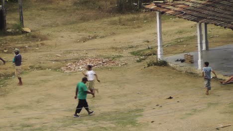 Vogelperspektive-Auf-Kubanische-Kinder,-Die-In-Der-Abenddämmerung-Auf-Einem-Unbefestigten-Platz-In-Einer-Typischen-Ländlichen-Stadt-Ohne-Gute-Infrastruktur-Baseball-Spielen