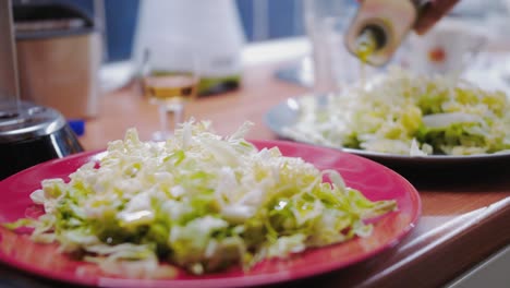 Gießen-Sie-Olivenöl-über-Gesunden-Salat-Auf-Einem-Parallaxenschuss-Auf-Einem-Roten-Teller