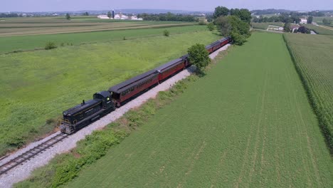 An-Aerial-View-of-a-Diesel-Locomotive-Pulling-Vintage-Passenger-Cars-Through-the-Amish-Countryside
