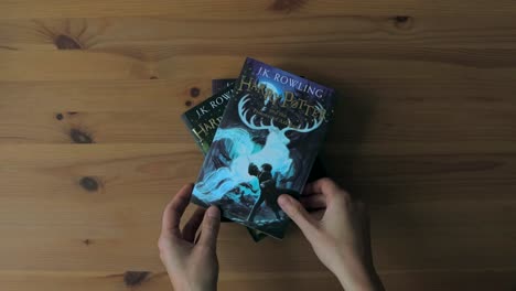 Hände-Stapeln-Englische-Harry-Potter-Bücher-übereinander-Auf-Einem-Holztisch