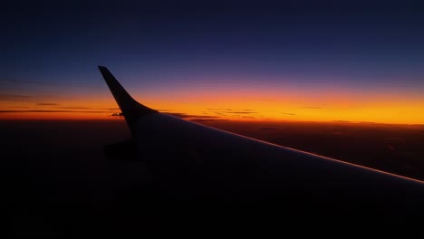 Gorgeous-red-and-orange-sunset-from-airplane-window,-left-wing-view