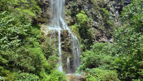 Zhangjiajie,-China---August-2019:-Menschen-Wandern-Auf-Einem-Malerischen-Pfad-Unterhalb-Des-Wunderschönen-Wasserfalls,-Der-Den-Berghang-Im-Majestätischen-Grand-Canyon-Im-Zhangjiajie-Nationalpark-Hinunterfällt