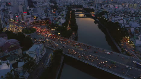 Evening-sunset-drone-shot-starting-from-the-horizon-and-tilting-down-to-Dien-Bien-Phu-Bridge-and-the-Hoang-Sa-canal-area-of-Binh-Thanh-district,-Saigon-or-Ho-Chi-Minh-City,-Vietnam