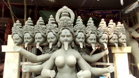 Incomplete-clay-idol-of-Indian-Goddess-Devi-Kali-kept-under-shed-of-workshop,-track-forward-and-tilt-camera-movement