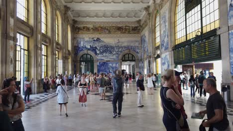 View-inside-crowded-Sao-Bento-Train-Station-in-Porto,-Portugal-to-far-wall-covered-in-azulejo-tile