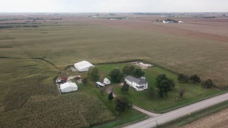 Luftdrohnenaufnahme-Eines-Ländlichen-Iowa-Eines-Hundertjährigen-Familienbauernhofs-Mit-Scheunen-Und-Maisfeldern