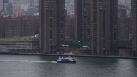 NYC-Ferry-sailing-on-East-River,-New-York-City-on-a-rainy,-foggy-morning