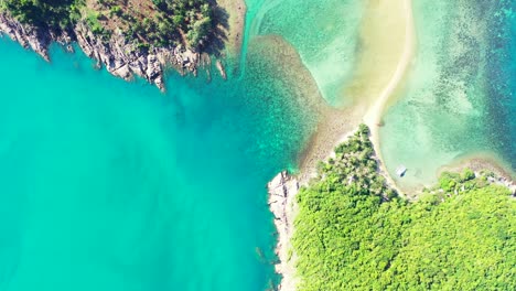 Grüne-Vegetation-Einer-Tropischen-Insel-Mit-Felsiger-Küste,-Umspült-Von-Einer-Ruhigen-Türkisfarbenen-Lagune-Voller-Korallenriffe-In-Thailand
