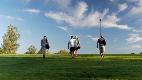 Slow-zoom-out-shot-of-four-guys-walking-up-a-hill-in-a-disc-golf-course