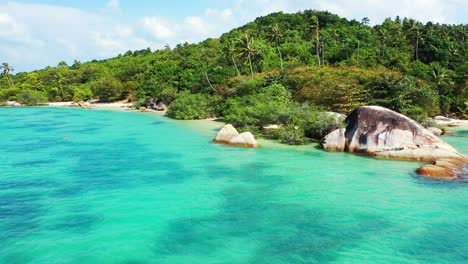 Paradise-exotic-beach-with-calm-clear-turquoise-lagoon-washing-beautiful-cliffs-and-white-sand-on-tropical-island-with-palm-trees-and-green-vegetation,-Thailand