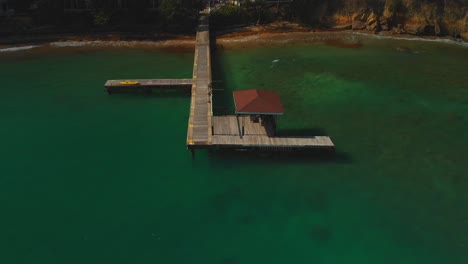 Erstaunliche-Luftaufnahme-Eines-Stegs-Mit-Krachenden-Wellen-Im-Hintergrund-In-Batteaux-Bay,-Tobago