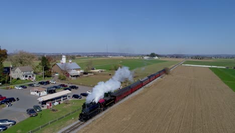 Aerial-view-of-an-antique-restored-steam-locomotive-with-passenger-cars-traveling-thru-countryside-as-it-is-blowing-black-and-white-smoke-and-steam
