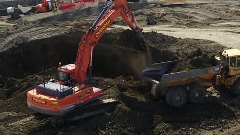 Vista-Aérea-De-Un-Camión-Volquete-Cargado-Por-Una-Gran-Excavadora