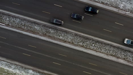 Aerial,-rising,-drone-shot,-top-down-above-traffic-on-parallel-roads,-some-snow-on-the-ground,-in-Helsinki-city,-on-a-overcast,-winter-day,-in-Finland