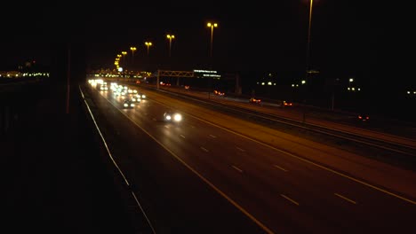 Car-headlights-at-night-on-highway,-camera-tilt-up-from-above-road
