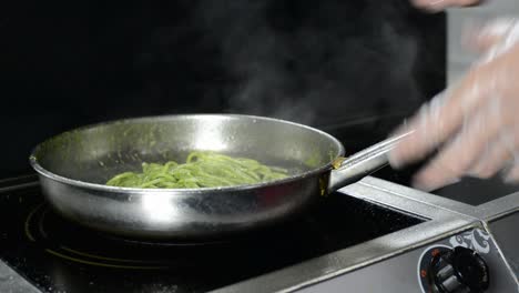 Spaghetti-in-a-fresh-green-pesto-sauce-cooking-and-tossed-in-frying-pan