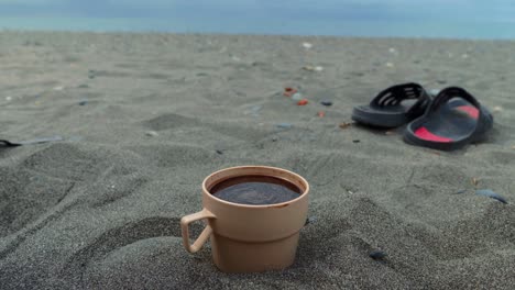 Spinning-coffee-in-the-plastic-cup-on-the-beach-of-black-sea,-Georgia