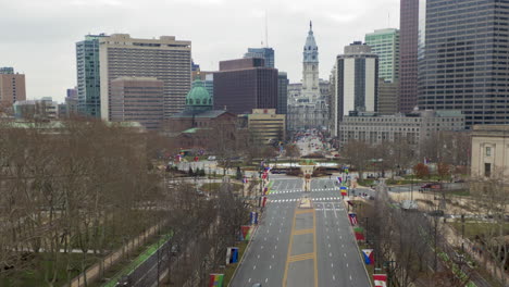 Downtown-Philadelphia-aerial-hyper-lapse,-Benjamin-Franklin-parkway-with-international-flags,-tilt-up-towards-City-Hall,-timelapse