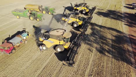 Men-spraying-off-the-combines-after-a-dusty-day-of-harvesting-corn---aerial-view