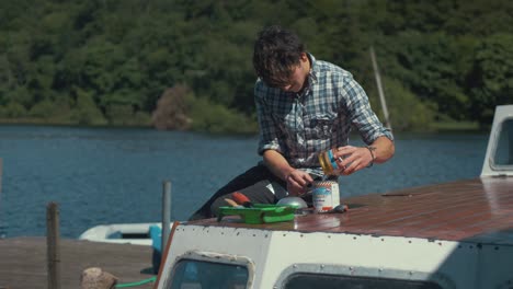 Young-carpenter-mixing-two-part-varnish-together-on-wooden-boat