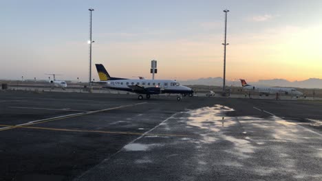 Jets-Vip-Lear-En-Posición-De-Estacionamiento-En-El-Aeropuerto-Internacional-De-Ciudad-Del-Cabo-Aeródromo-Ejecutivo-Privado-Con-Puesta-De-Sol-Dorada-Sobre-La-Silueta-De-La-Montaña-De-La-Mesa-Y-Asfalto-Mojado