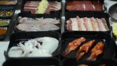 Flavored-Meats-And-Seafood-Along-With-A-Bunch-Of-Sauces-On-Black-Containers