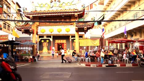 Gente-Comiendo-En-Puestos-De-Comida-Callejera-Y-En-La-Concurrida-Calle-Frente-Al-Santuario-De-Kuan-Yin-En-El-Barrio-Chino-De-Bangkok-Que-Muestra-La-Vida-Cotidiana-Y-La-Cultura-De-La-Comunidad-China-En-Tailandia