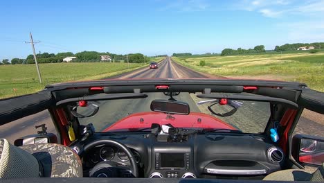 POV-Driving-on-a-paved-road-in-rural-South-Dakota,-viewing-farms-and-fields