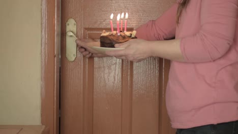 Woman-carrying-chocolate-birthday-cake-with-candles-medium-shot