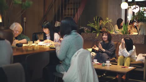 Clientes-Japoneses-Charlando-Y-Trabajando-Dentro-De-Un-Café-En-Kyoto,-Japón