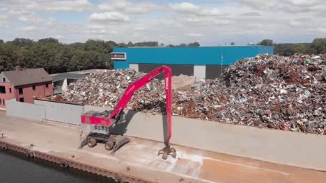 Mosca-Aérea-Por-Un-Depósito-De-Chatarra-De-Metal-De-Reciclaje-Con-El-Río-Twentekanaal-En-Primer-Plano-Contra-Un-Cielo-Azul-Con-Nubes