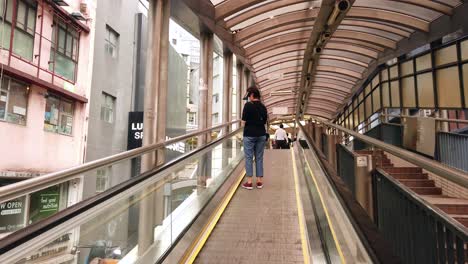 Corona-Virus-Pandemic,-Local-Commuters-using-an-escalator-in-downtown-Hong-Kong,-wearing-protective-face-masks