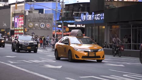 Taxi-Amarillo-De-La-Ciudad-De-Nueva-York-Conduciendo-A-Través-Del-Tráfico-Abarrotado-En-Time-Square-En-Cámara-Lenta-Durante-El-Día