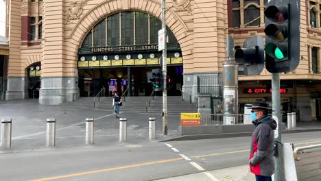 Ein-Mann-Mit-Schutzmaske-Wartet-Darauf,-Während-Des-Covid-19-Ausbruchs-In-Australien-Die-Gespenstisch-Ruhigen-Straßen-Der-Stadt-Melbourne-Zu-überqueren