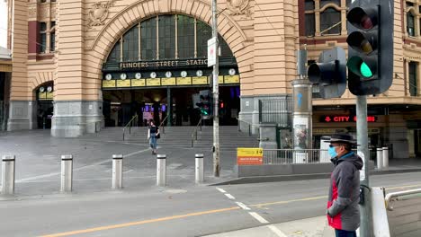 Hombre-Con-Una-Máscara-Protectora-Espera-Para-Cruzar-Las-Calles-Fantasmagóricas-Y-Tranquilas-De-La-Ciudad-De-Melbourne-Durante-El-Brote-De-Covid-19-En-Australia