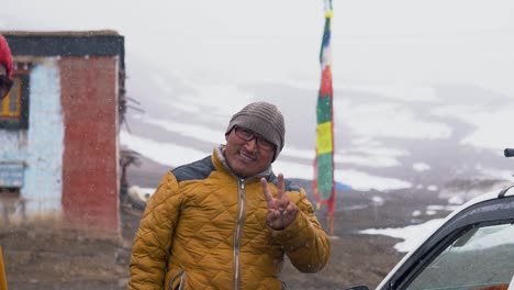 During-Snowfall,-a-Buddhist-Monk-Cheering-and-Showing-Thumbs-Up-sign-to-the-camera-a-Monastery-Near-in-Komic-Village-near-Spiti,-a-Remote-Town-in-the-Himalayas