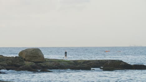 Person-on-Paddle-Board-on-Rocky-Ocean-Coast-in-Sydney,-Australia