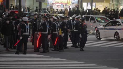 Policías-Con-Bastón-Led-De-Pie-En-El-Cruce-De-Shibuya-Scramble-En-La-Noche-De-Halloween-En-Tokio,-Japón