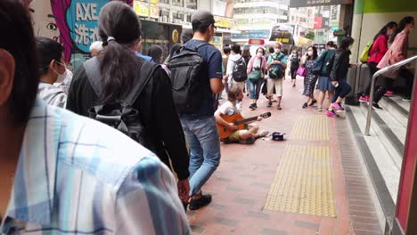 Ejecutante-De-La-Calle-Tocando-Una-Guitarra-En-El-Centro-De-Hong-Kong-Con-Los-Lugareños-Que-Pasan