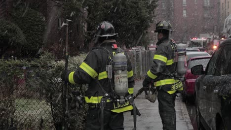 Bomberos-Parados-Bajo-Fuertes-Nevadas-En-La-Calle-Brooklyn-Asistiendo-A-Una-Emergencia---Plano-Medio