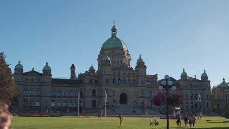 Wide-shot-of-the-Legislative-Assembly-of-British-Columbia-in-Victoria,-BC-on-a-gorgeous-sunny-day-with-blue-skies-and-people-walking-around-on-green-grass