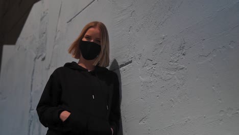 Portrait-of-Young-Attractive-Female-in-Black-Clothes-and-Face-Mask-Looking-at-Camera,-Slow-Motion